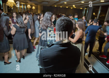 La vita notturna di concetto di concerto. Dj stand torna alla telecamera di fronte alla folla di onorevoli bello mans danza nel buio, sollevato in alto le mani e a gridare forte . DJ indietro Foto Stock