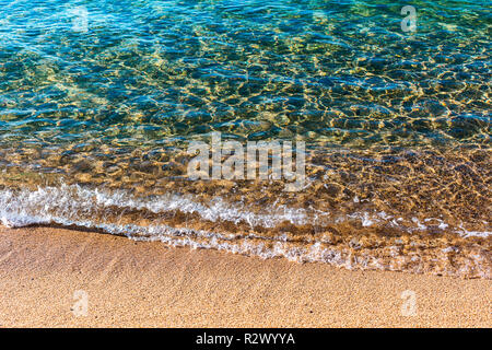 Spiaggia di sabbia di mare caldo. Trasparenti acque turchesi, onda morbida, riflettendo la luce del sole sul fondo del mare Foto Stock