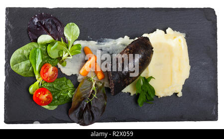 La morcilla servito su purea di patate e carote, cherry pomodoro e insalata. Isolato su sfondo bianco Foto Stock