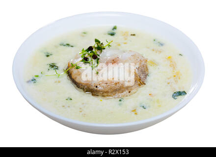 Una deliziosa minestra con eglefino affumicato, patate e cipolle servito con verdi in vaso bianco - piatto tradizionale della cucina scozzese. Isolato su bianco b Foto Stock