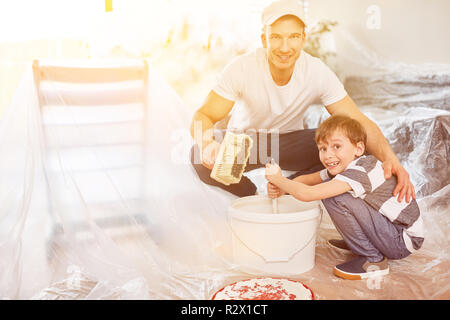 Figlio aiuta a suo padre un mix di colore per pittura mentre home lavori di rinnovo Foto Stock