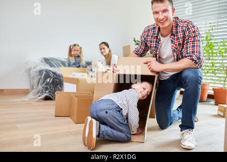 Padre e figlio nella nuova casa a giocare mentre si è in movimento con scatola di movimentazione Foto Stock
