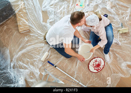 Coppia felice kissing mentre il rinnovamento mentre la pittura nella nuova casa Foto Stock