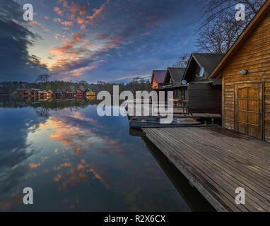 Tata, Ungheria - bel tramonto sul lago Derito Derito (a) nel mese di novembre con la pesca in legno cottages e colorato Cielo e nubi Foto Stock