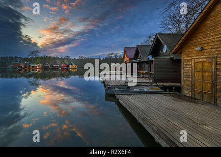 Tata, Ungheria - bel tramonto sul lago Derito Derito (a) nel mese di novembre con la pesca in legno cottages e colorato Cielo e nubi Foto Stock