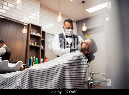 Hipster uomo client haidresser visita e un parrucchiere in un barbiere. Foto Stock