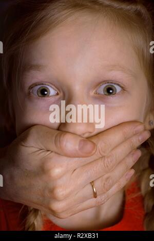 Abuso di minori - l'adulto chiude bambino la bocca con la mano Foto Stock