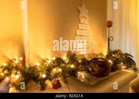 Albero di Natale con decorazioni vintage vicino al camino, luci a LED, decorazione dorata per Natale Foto Stock