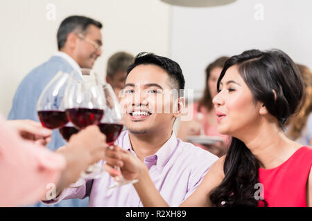 Coppia wineglasses tostatura con gli amici Foto Stock
