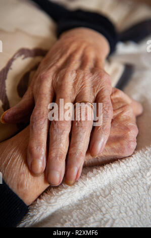 Vecchia Signora con le mani in mano che mostra l'età e l'oro wedding band. Foto Stock