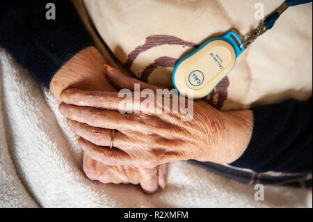 Vecchia Signora con le mani in mano che mostra l'età, il pulsante di allarme e oro wedding band. Foto Stock