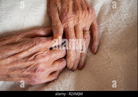 Vecchia Signora con le mani in mano che mostra l'età e l'oro wedding band. Foto Stock