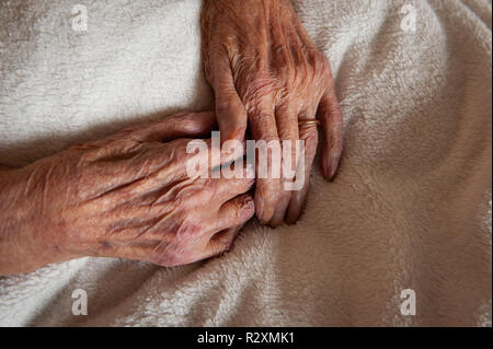 Vecchia Signora con le mani in mano che mostra l'età e l'oro wedding band. Foto Stock