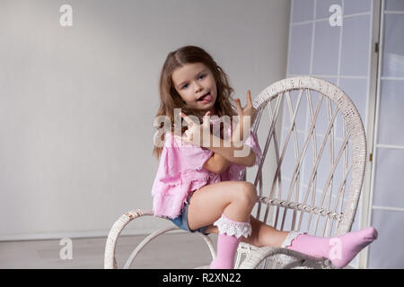 Bella moda bambina si siede su una sedia Foto Stock
