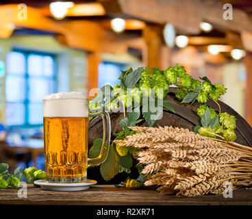 Bicchiere di birra con il luppolo e orzo sul barile di legno Foto Stock