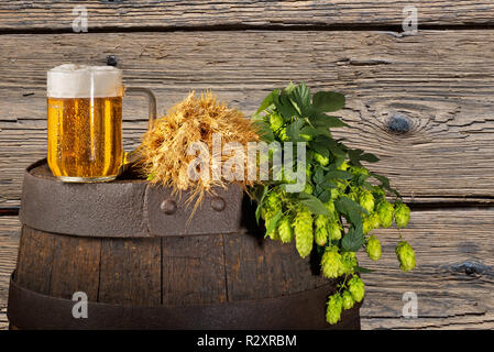 Bicchiere di birra con il luppolo e orzo sul barile di legno Foto Stock