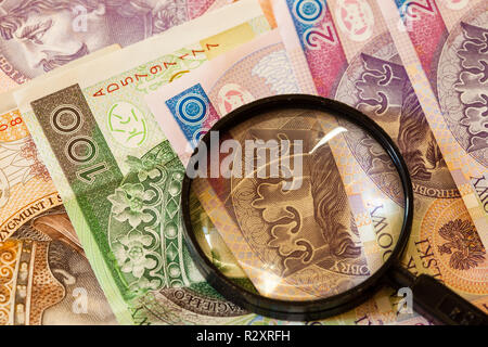 La contraffazione di denaro concetto. Zloty polacco banconote moneta e lente di ingrandimento Foto Stock