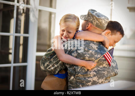 Metà uomo adulto vestito in uniforme militare è accolto dai suoi figli. Foto Stock