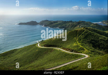 Automobile che viaggia lungo una strada tortuosa verso la punta di una penisola in campagna. Foto Stock