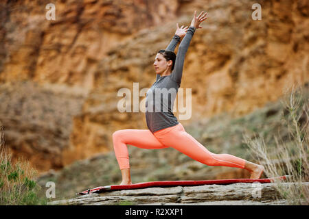 Giovane donna stretching su una roccia. Foto Stock