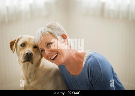 Felice donna matura avvolge il suo Golden Labrador. Foto Stock