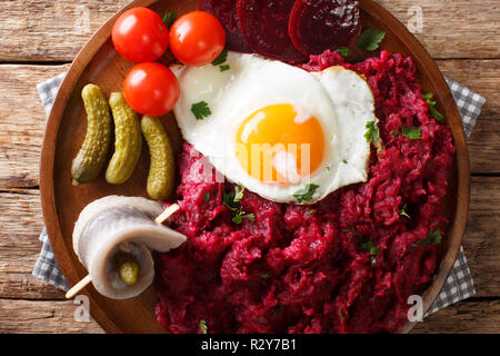 Labskaus è un tradizionale del nord piatto di patate, corned beef e bietole con uovo fritto, sottaceti e aringhe close-up su una piastra sul tavolo. orizz. Foto Stock