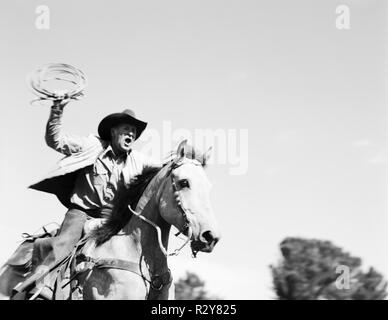 Coppia cowboy a cavallo ed oscillante un laccio all'esterno. Foto Stock