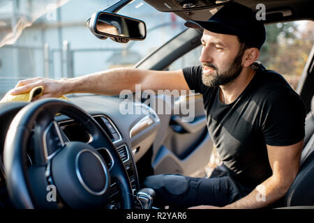 Rondella di bello in black t-shirt e tappo tergi pannelli di un auto di lusso con interni in microfibra giallo Foto Stock