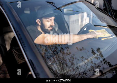 Rondella professionale tergi pannelli auto con giallo microfibra, vista attraverso il parabrezza Foto Stock