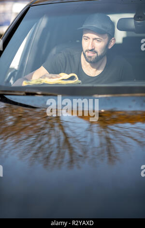 Rondella professionale tergi pannelli auto con giallo microfibra, vista attraverso il parabrezza Foto Stock