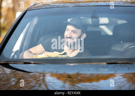 Rondella professionale tergi pannelli auto con giallo microfibra, vista attraverso il parabrezza Foto Stock