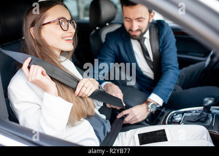Businesman cinghia di fissaggio di una donna di preoccuparsi per la sua sicurezza in auto Foto Stock
