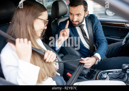 Businesman cinghia di fissaggio di una donna di preoccuparsi per la sua sicurezza in auto Foto Stock