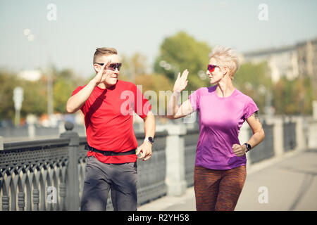 Foto di sport giovane facendo stretta di mano che corre lungo argine sulla mattina d'estate Foto Stock