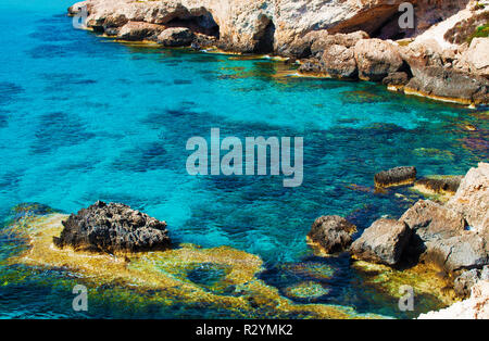 Sullo sfondo di un mare di fondo e superficie di colore giallo e con pietre bianche vicino increspata trasparente crystal clear incredibile verde e blu dell'acqua. Il caldo estivo d Foto Stock