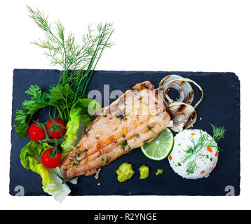 Vista dall'alto di arrosto di filetto di trota con riso bianco e grigliate di cipolle, verdure fresche, verdi, calce e guacamole su nero che serve board. Isolate su w Foto Stock