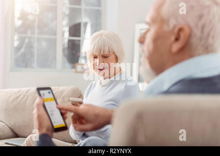 Paio di eleganti pensionati controllo previsioni meteo Foto Stock