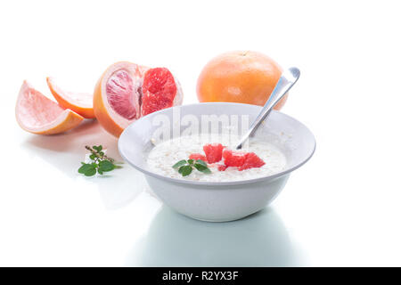 Dolce di farina di avena con fette di pompelmo rosso in un vaso in ceramica isolata su sfondo bianco Foto Stock