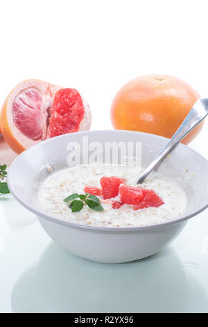 Dolce di farina di avena con fette di pompelmo rosso in un vaso in ceramica isolata su sfondo bianco Foto Stock