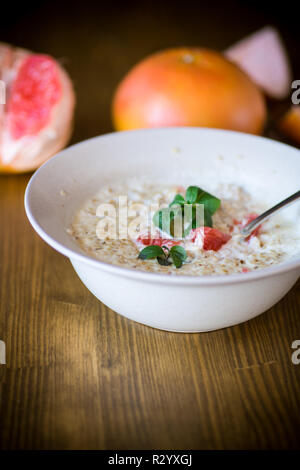 Dolce di farina di avena con fette di pompelmo rosso in un vaso in ceramica isolata sul tavolo di legno Foto Stock