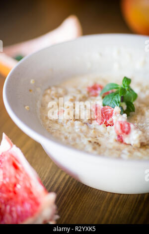 Dolce di farina di avena con fette di pompelmo rosso in un vaso in ceramica isolata sul tavolo di legno Foto Stock