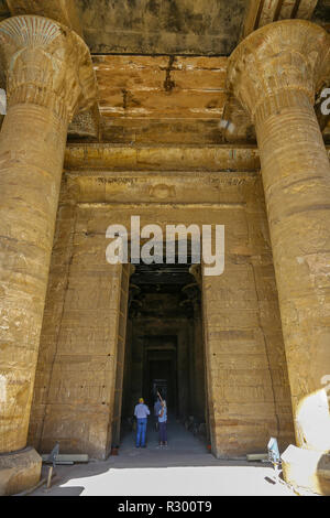 Due persone che guardano le colonne del Tempio di Edfu, un tempio egizio situato sulla sponda ovest del Nilo in Edfu, Alto Egitto, Nord Africa Foto Stock