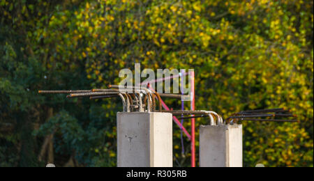 Vista ravvicinata delle aste in acciaio che sporgono da pilastri in cemento armato in un cantiere. Nessuna gente. Spazio di copia Foto Stock