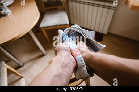 Un uomo delle salviette le mani con un asciugamano da cucina. Ampio angolo di prospettiva in prima persona. Foto Stock