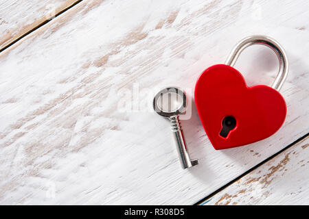Lucchetto rosso cuori con chiave su bianco sullo sfondo di legno. Copyspace Foto Stock