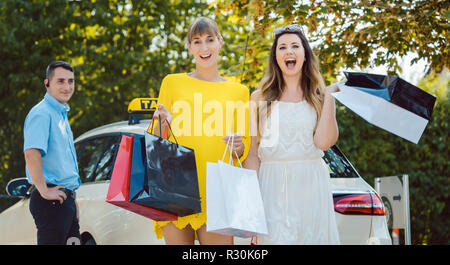 Le donne con le borse della spesa in uscita di taxi Foto Stock