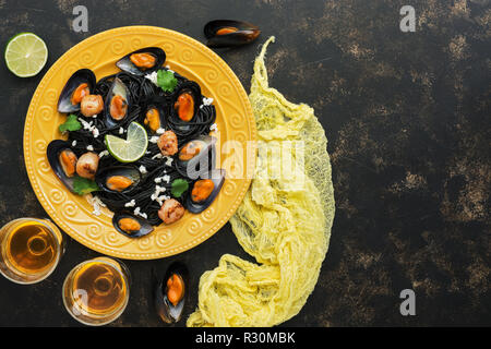 Pasta nera gli spaghetti con le cozze, capesante e vino bianco su uno sfondo rustico. Cucina mediterranea. Vista superiore, spazio di copia