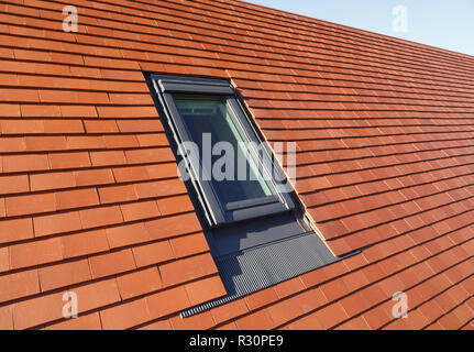 Tipo Velux sul tetto finestra di luce in una pianura tradizionali piastrelle in argilla tetto della casa Foto Stock