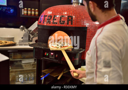 Pizza cucina con cuochi di mettere la pizza in forno su lunga pagaia, STATI UNITI D'AMERICA Foto Stock