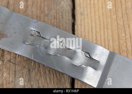 Incollaggio di un foglio di lamiera servendosi di una pinza per crimpare. Piccoli lavori metalmeccanici in una officina meccanica. Sfondo scuro. Foto Stock